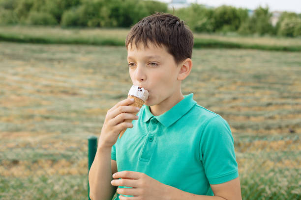 garoto de 11 anos comendo um sorvete. adolescente de férias, verão, momento de suor - 10 11 years cheerful happiness fun - fotografias e filmes do acervo