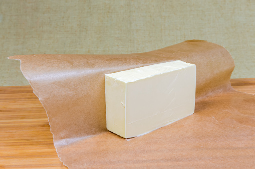 Female hands cutting butter next to a bowl of eggs during cake preparation