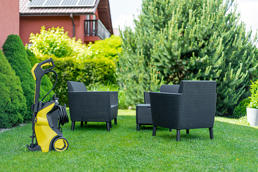 Cleaning garden furniture with high pressure washer. Outdoor, back yard.