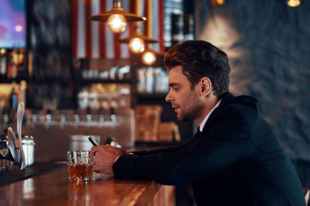 istock Side view of handsome young man in full suit using smart phone 1325401741