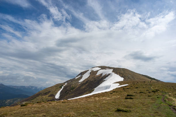 istock Spring mountains in snow and green grass 1325403914