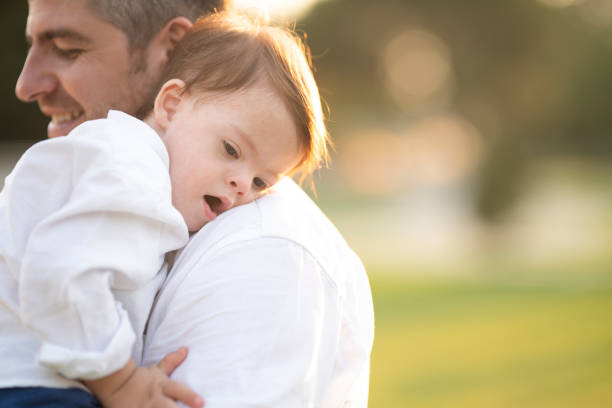 Little boy with down syndrome is hugging her father at sunset.
