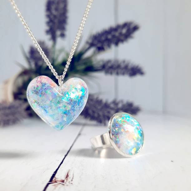 Hand made art jewelry, transparent heart-shaped pendant and ring with glitter inside, epoxy resin Hand made art jewelry, transparent heart-shaped pendant and ring with glitter inside, epoxy resin silver necklace and silver ring resin jewelry stock pictures, royalty-free photos & images