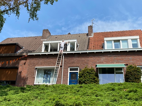 Brunssum, the Netherlands, - June 25, 2021. House painter in action on a sunny summer day.