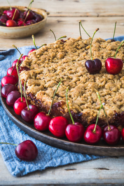 istock Cherry pie with sprinkles, cherry crumble, and fresh cherries on a rustic wooden background, vertical 1325411706
