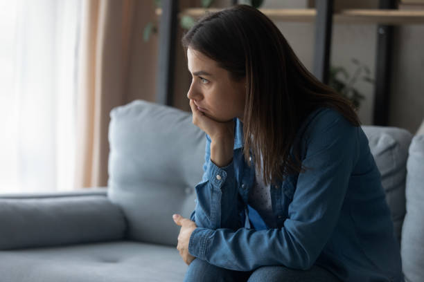 istock Unhappy young woman thinking of problems, sitting on sofa. 1325412539
