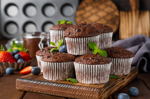 istock Chocolate muffins or cupcakes with chocolate drops on a dark wooden background with fresh berries and mint. Copy space. 1325413565