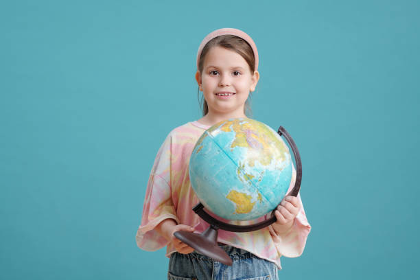 istock Cute smiling schoolgirl holding globe 1325413626