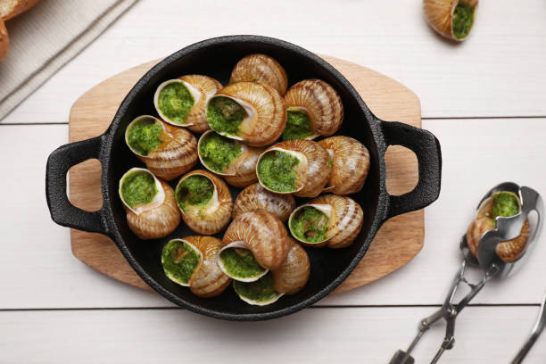 白い木製のテーブルの上に提供されるおいしい調理されたカタツムリ、平らな横たわって - gourmet snail food escargot ストックフォトと画像