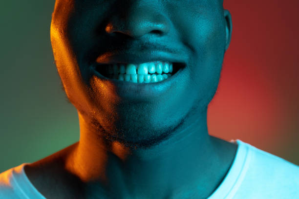 Cropped portrait of young african man on bright studio background in neon light. Concept of human emotions, facial expression, youth.