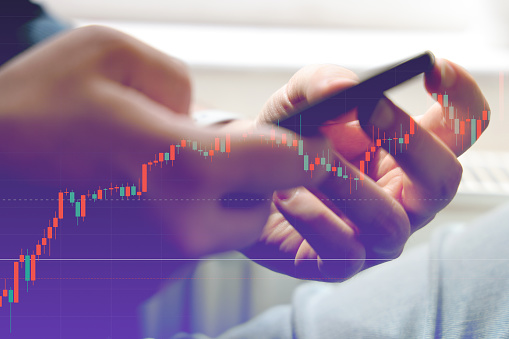 Trader holding smartphone with graphs analysis candle line