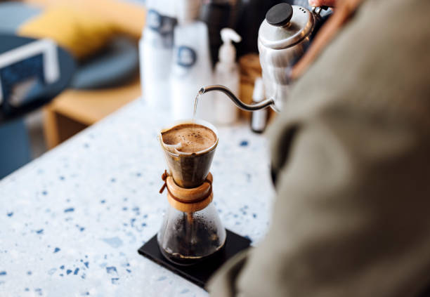 Unrecognizable Bartender Preparing Drip Coffee in a Cafe High angle view of professional barista pouring boiling water from a metal teapot into a glass kettle in a coffee shop coffee filter stock pictures, royalty-free photos & images