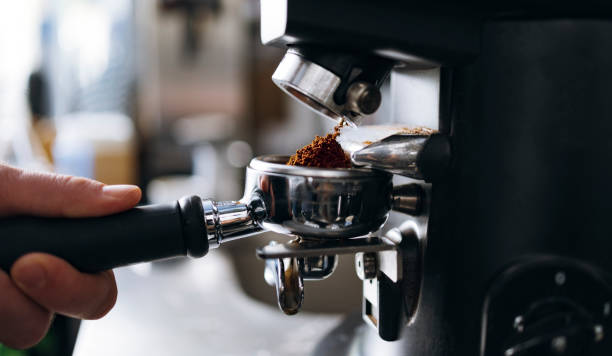 macinazione professionale caffè appena tostato in una macchina per caffè espresso - grinding foto e immagini stock