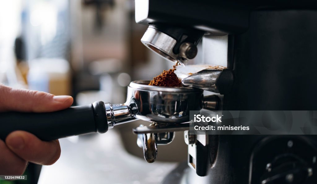 Professional Grinding Freshly Roasted Coffee in a Espresso Machine Close up photo of unrecognizable barista preparing coffee in a coffee shop Coffee - Drink Stock Photo