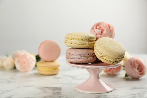 Delicious macarons and flowers on white marble table