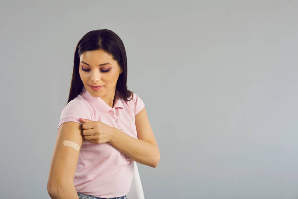 istock Woman looking at medical patch on hand standing over studio copy space 1325420593