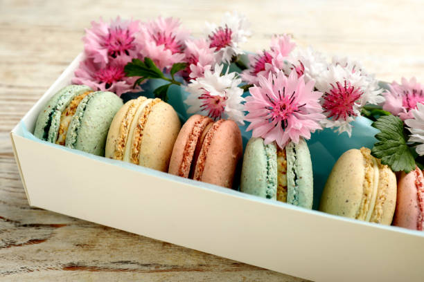istock Delicious macarons and flowers in box on white wooden table 1325420636