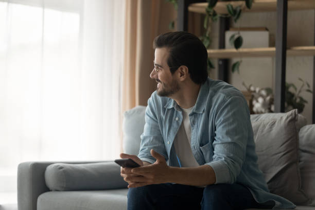 istock Dreamy young man holding cellphone in hands. 1325420989