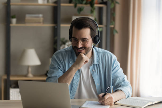 istock Happy young man listening educational online lecture on computer. 1325421013