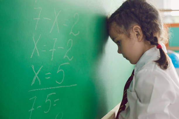 istock Back to school. Little schoolgirl has a problem with a math problem on a school board in the classroom. Upset child thinks in class 1325421428