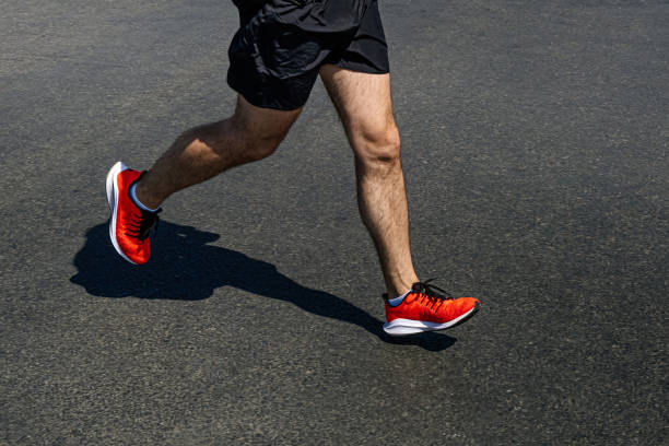 istock legs runner man in bright orange shoes run on dark asphalt 1325422603