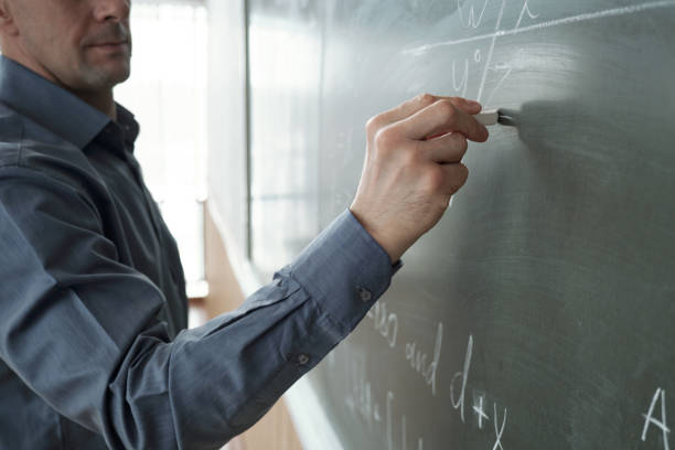 istock Contemporary teacher writing formula on chalkboard 1325422809