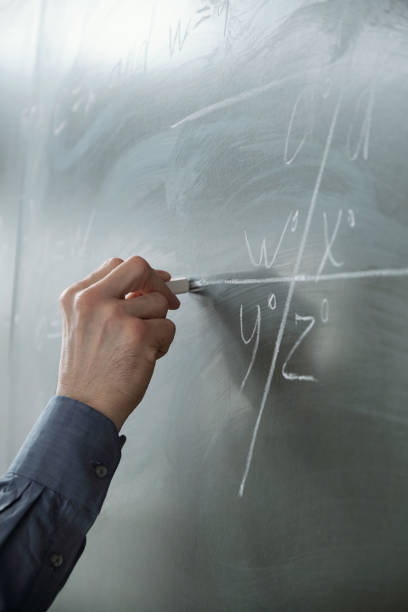 istock Hand of teacher with chalk by blackboard during explanation 1325422813