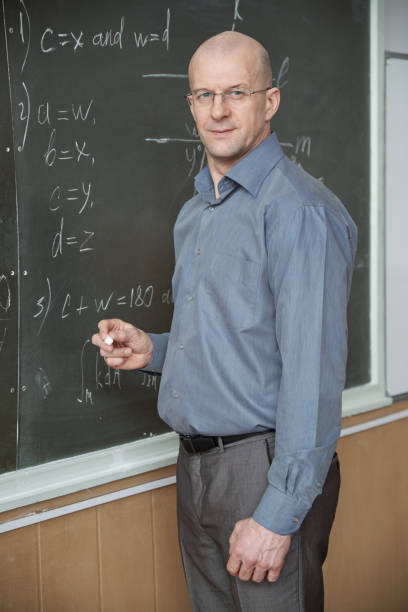 istock Confident teacher standing by blackboard with formulas 1325422814