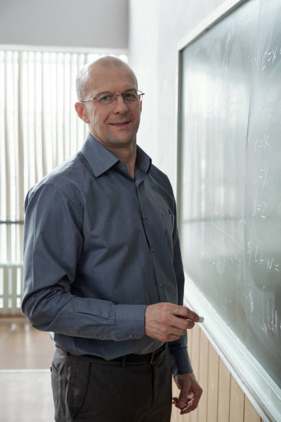 istock Happy professor standing by blackboard 1325422827