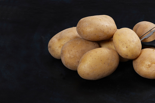 Old Raw Potatoes awaiting cooking on black background. High resolution 45Mp images using Canon EOS R5 and associate lenses