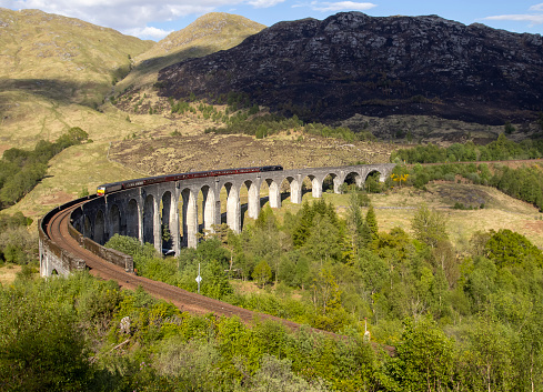 The Jacobite Steam Train crossing the Glenfinnan Viaduct near Fort William in the Scottish Highlands, UK
