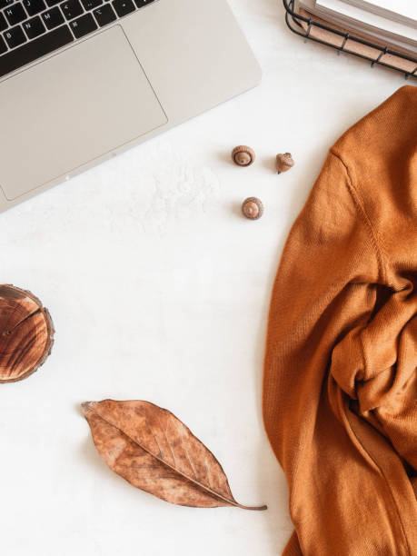 istock Home office desk with laptop, storage basket, brown sweater, fall leaf and acorns 1325426273