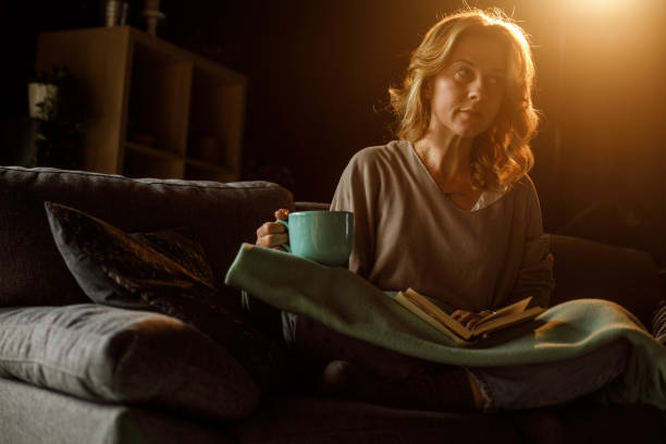 istock Woman reading a book late at night while relaxing on the sofa 1325434696