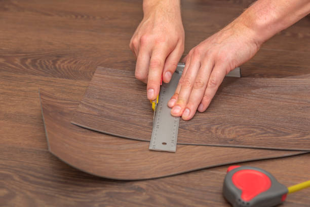 DIY vinyl flooring. Easy installation and cutting with a knife, Master cuts vinyl plank before installation, brown heated floor. Copy space