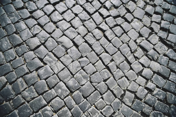 istock Abstract black background of old rough granite paving stones with light reflection 1325442678