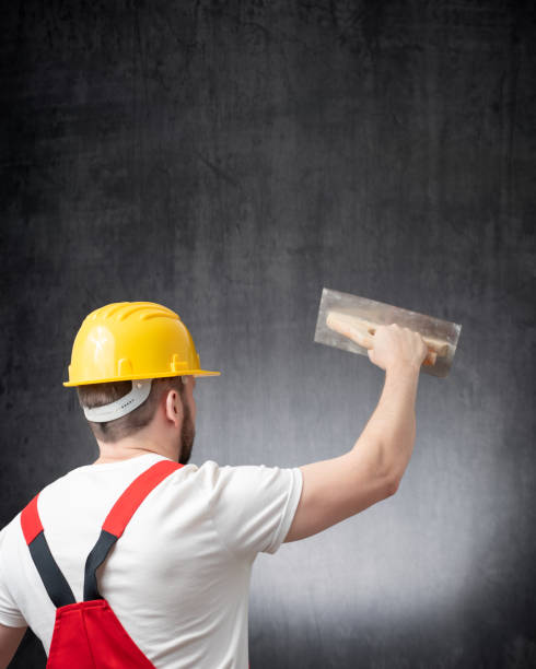 Rear view of a worker plastering a wall indoors