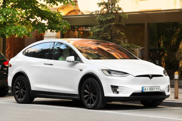 White Tesla Model X white electric car parked in the city Kiev, Ukraine - May 22, 2021: Tesla Model X white electric car parked in the city tesla model x stock pictures, royalty-free photos & images