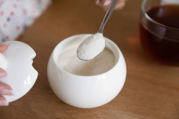 close up woman putting spoon of sugar in black tea - sugar spoonful imagens e fotografias de stock