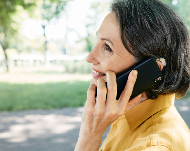 Mature woman with hearing aid has a full life and can hear interlocutor on phone. Hearing solution and innovation technology Mature woman with hearing aid has a full life and can hear interlocutor on phone. Hearing solution and innovation technology hearing aid photos stock pictures, royalty-free photos & images