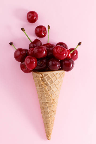 istock Ice cream cone filled with cherries on a pink background. Fresh cherry in a waffle cone. Summer concept 1325453566