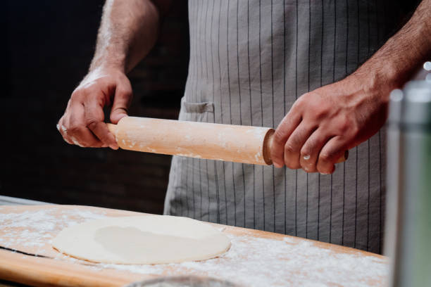 istock hands roll the dough into a thin layer. Cooking pizza, noodles or pitta at home 1325455618
