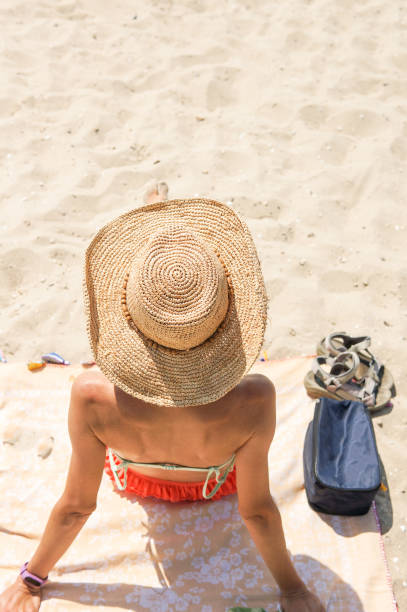 istock tanning woman wearing sun hat at the beach 1325468489