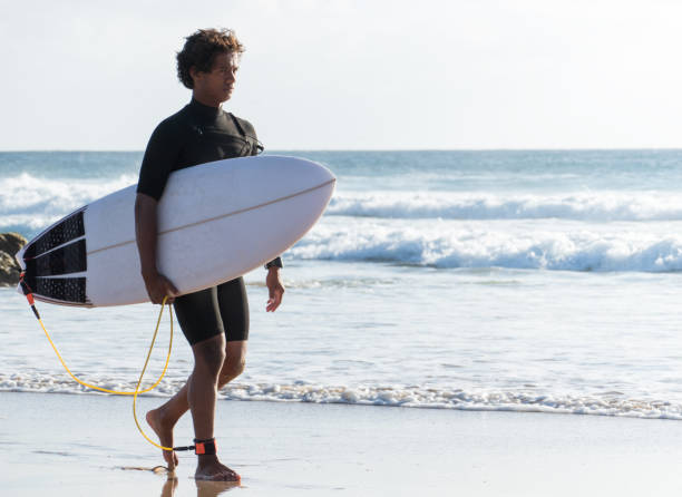 istock Young malagasy african surfer walking by the beach shore with his surfboard 1325470287