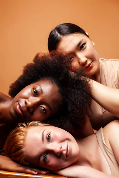 young pretty asian, caucasian, afro woman posing cheerful together on brown background, lifestyle diverse nationality people concept stock photo