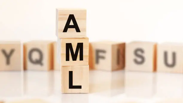 wooden cubes with word AML arranged in a vertical pyramid, on the white background is a row of wooden cubes with letters, business concept. AML - short for ANTI-MONEY LAUNDERING