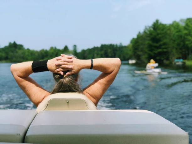 Fit and pretty senior woman on a pontoon adventure. stock photo