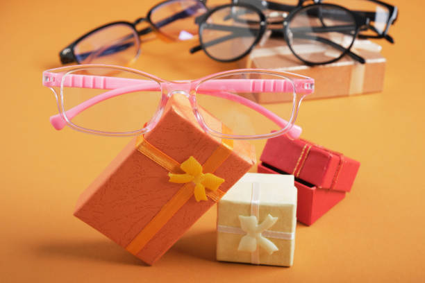 istock pink glasses for girls on small gift boxes, small gift boxes on a brown background copy space, 1325484604