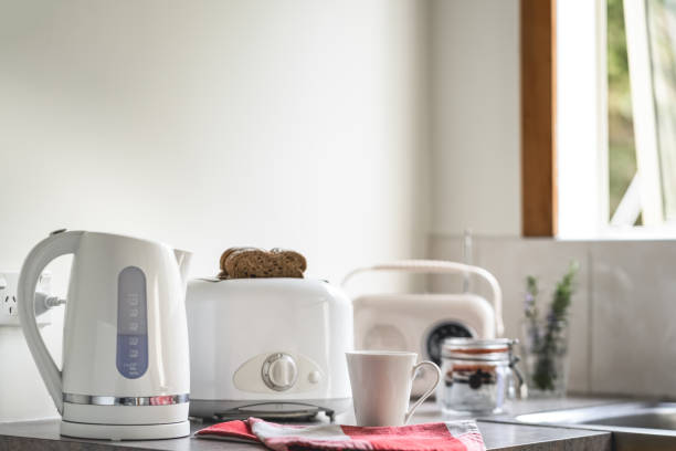 Breakfast table with white appliances, electric kettle toaster, mug and vintage radio stock photo