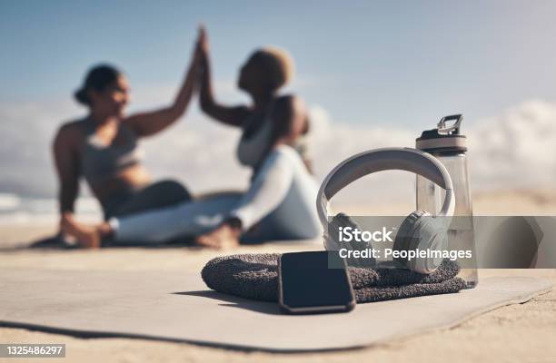 Shot of a cellphone, headphones, towel and water bottle on the beach