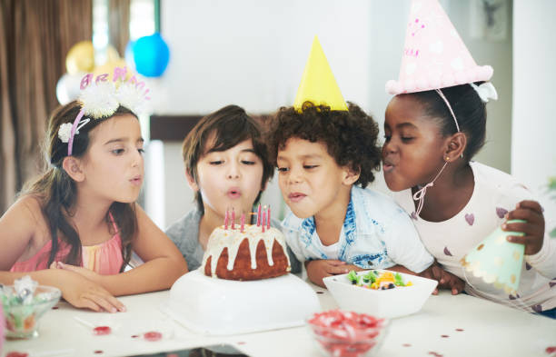 strzał z czterech uroczych dzieci świętujących razem na imprezie urodzinowej - kids birthday party zdjęcia i obrazy z banku zdjęć